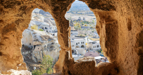 Vue sur le village troglodytique de Çavuşin à travers l’ouverture d’une habitation creusée dans la roche, en Cappadoce.